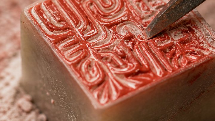 Close detail of carved Chinese seal face, knife marks, red paste, and stone dust