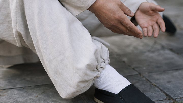Close detail of Taijiquan hands, cloth shoes, and stone courtyard floor
